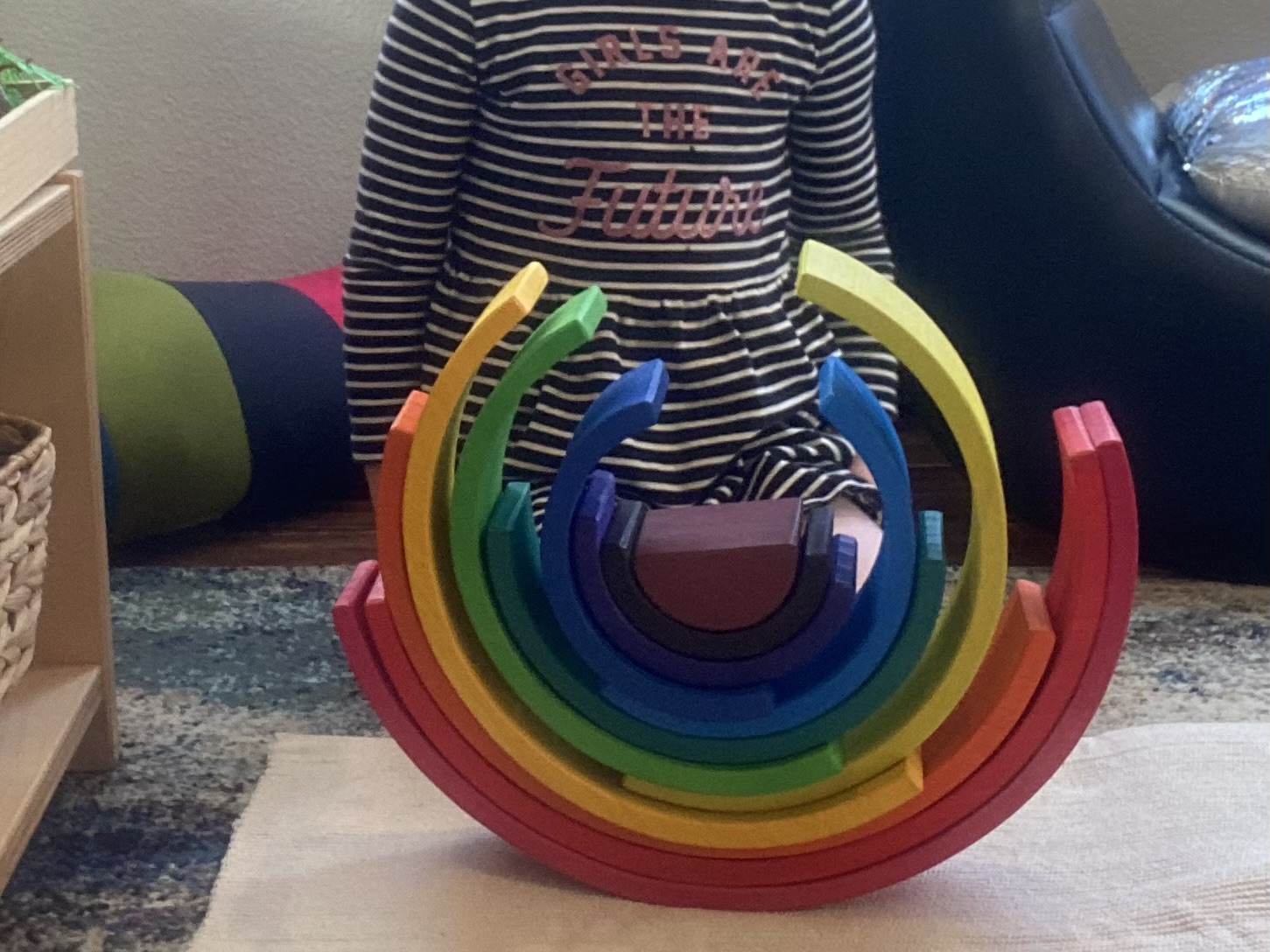 Child balancing arches from a wooden rainbow stacker