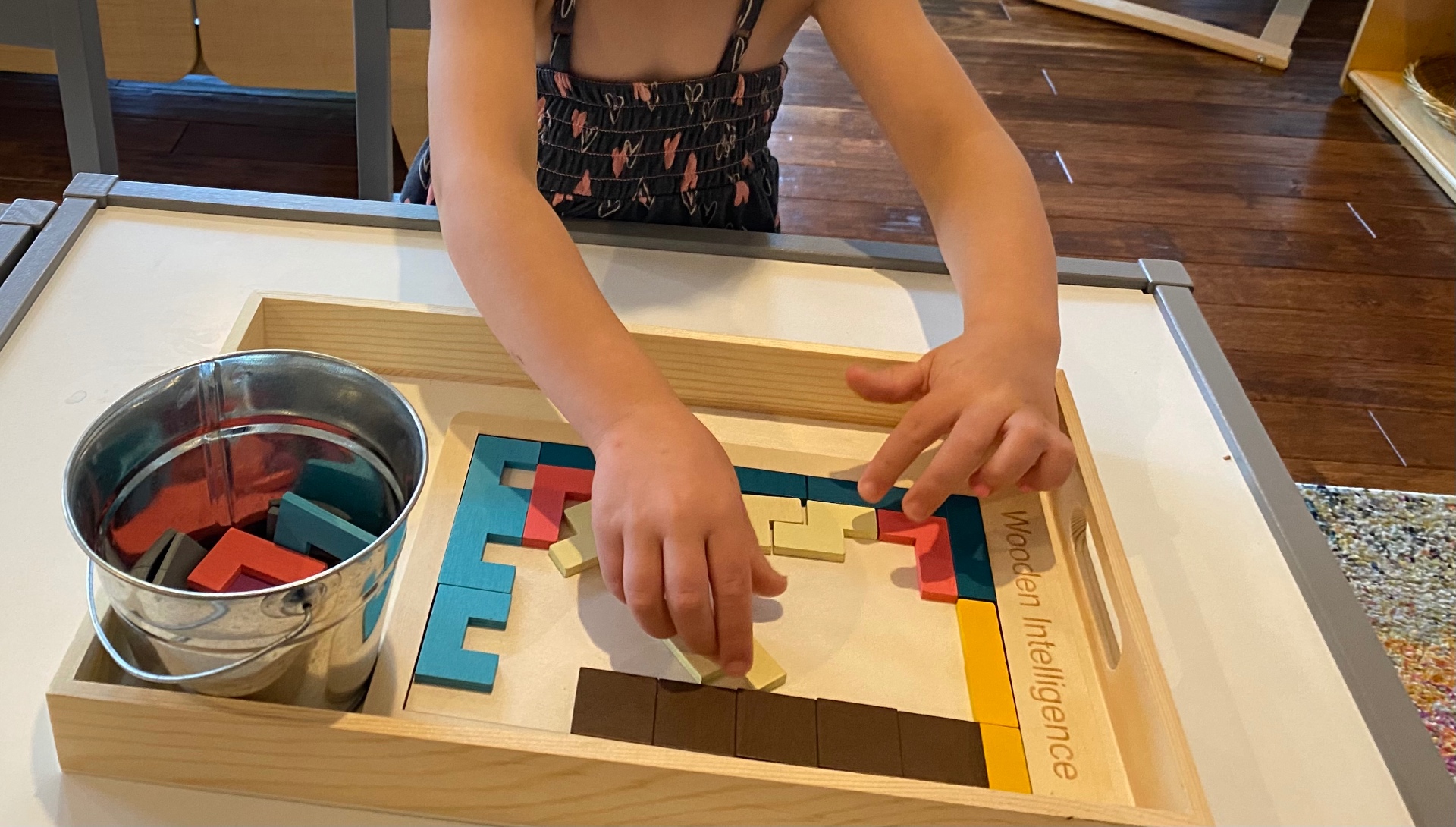 A child at Whitney's House concentrating on a wooden Montessori block puzzle